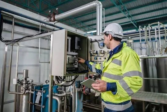 Technician checking equipment controls in an industrial facility